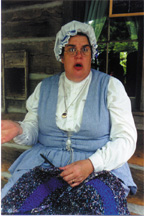 this photo show Judy seated on the porch of the Homestead cabin at Silver Dollar City telling a story
